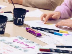 Personas practicando lettering con rotuladores de colores durante un taller creativo
