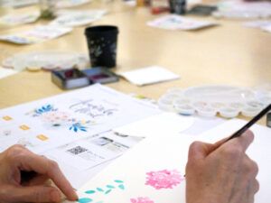 Persona pintando flores y hojas con acuarela durante un taller de acuarela floral en Madrid